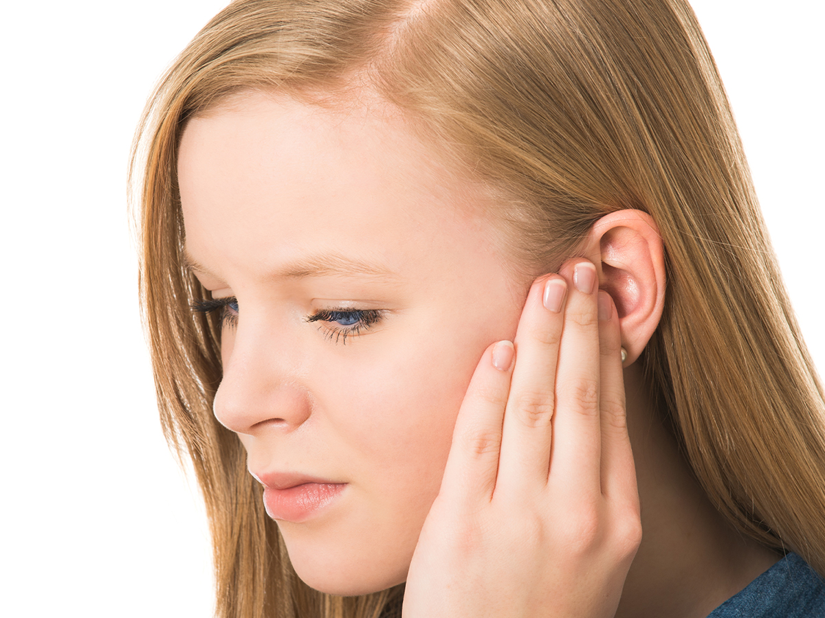 Woman holding her hand over her ear.