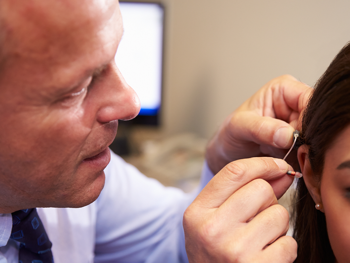 Doctor placing a small ear device inside a girl's ear.