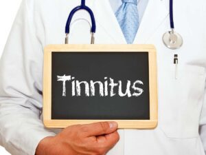 A doctor holding up a chalkboard with the word "Tinnitus" written on it