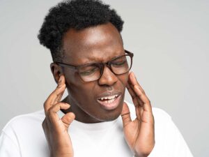 African American man holding his ears in pain