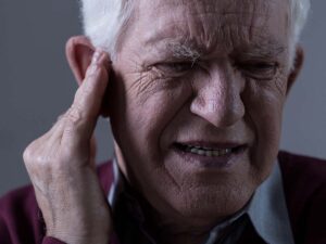 An old man covering his ear while in pain