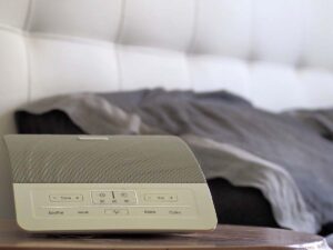 A white noise machine next to a person's bed