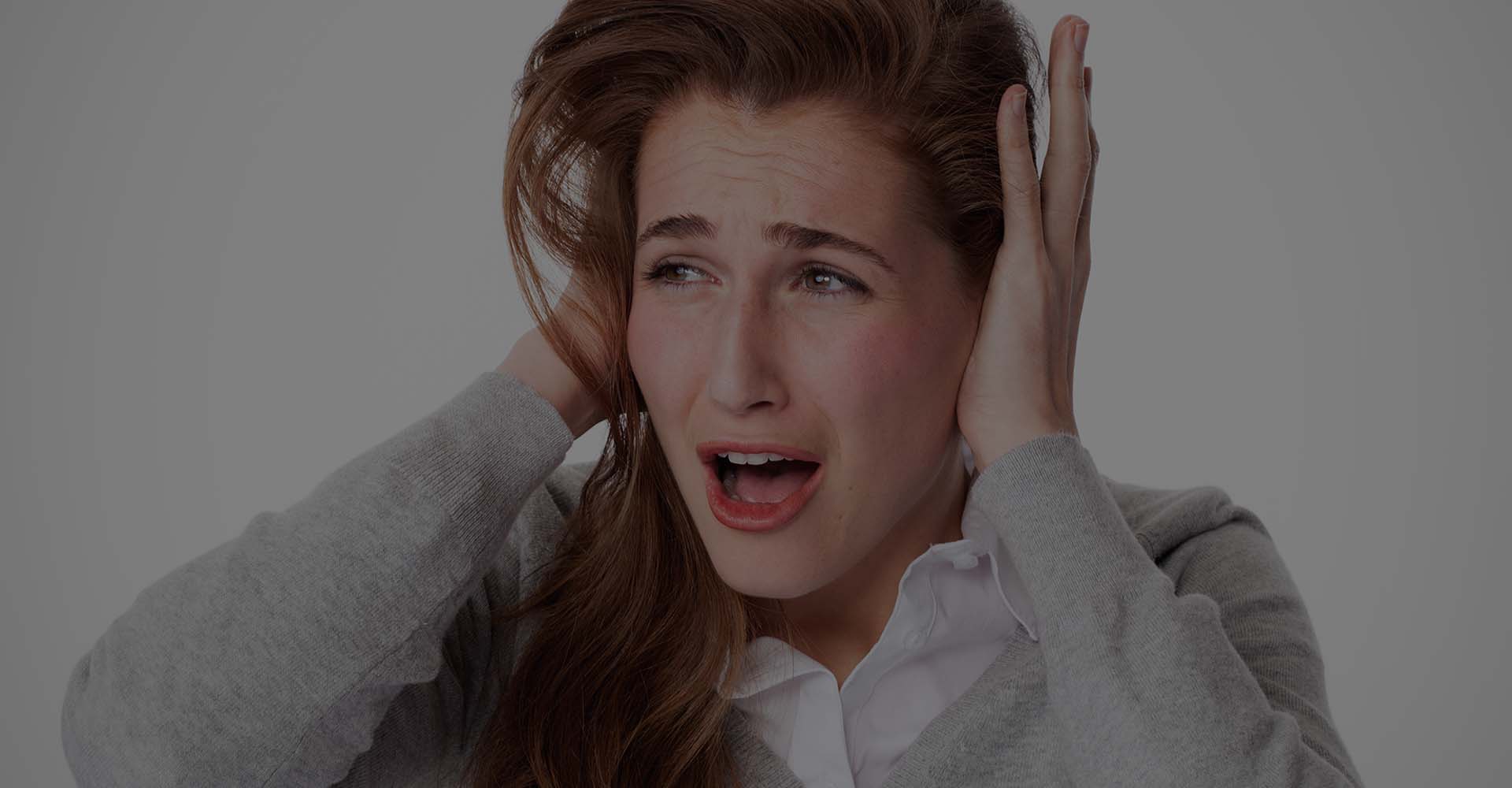 A woman in pain covering her ears