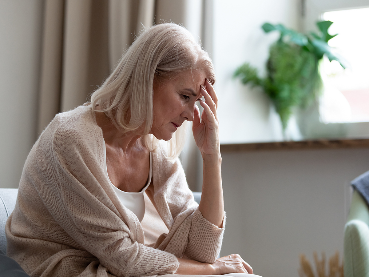 elderly person with migraine holding forehead