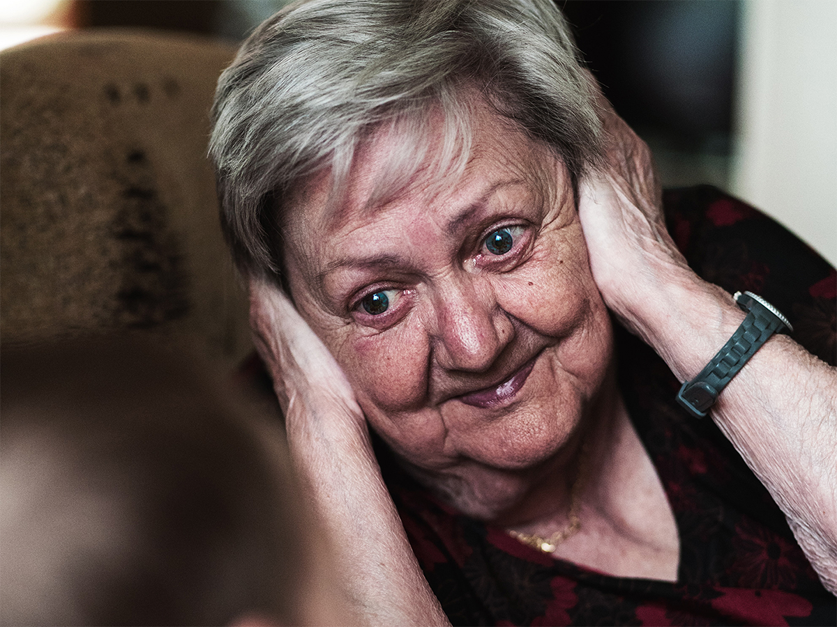 older woman holding her ears