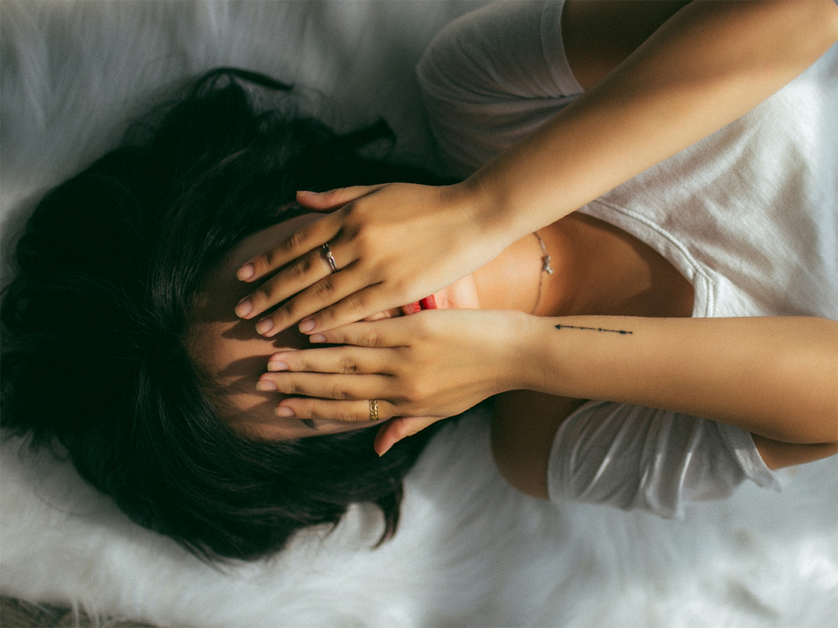 person lying down with hands over face