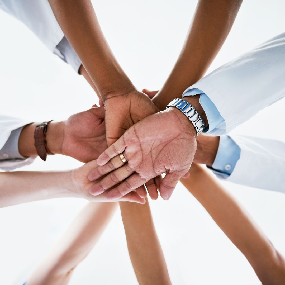 hands piled on top one another to show working together