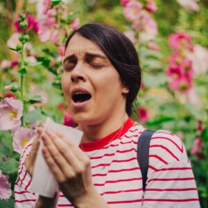 woman sneezing because of seasonal allergies