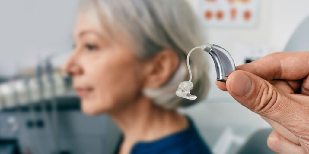 A doctor holding a hearing aid next to an older woman