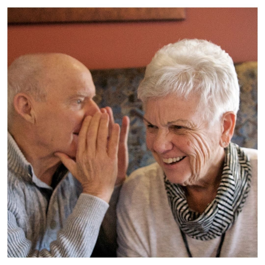 man talking into woman's ear